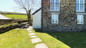 Un bâtiment en pierre avec un chemin pavé menant à une table de pique-nique.