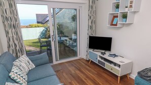 Una sala de estar con sofá, televisor y piso de madera.