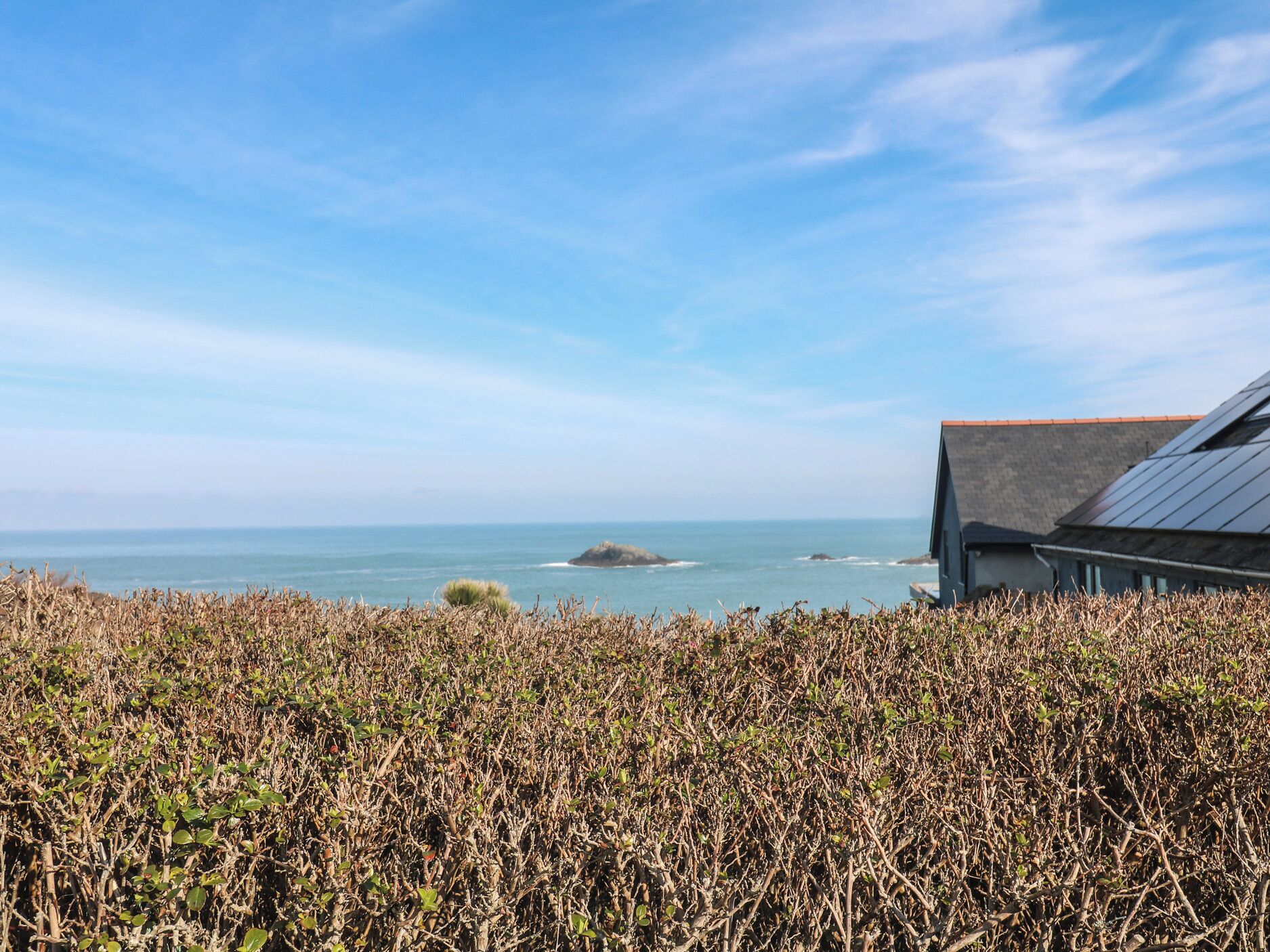 A coastal landscape with a view of the sea and a building with a sloped roof.