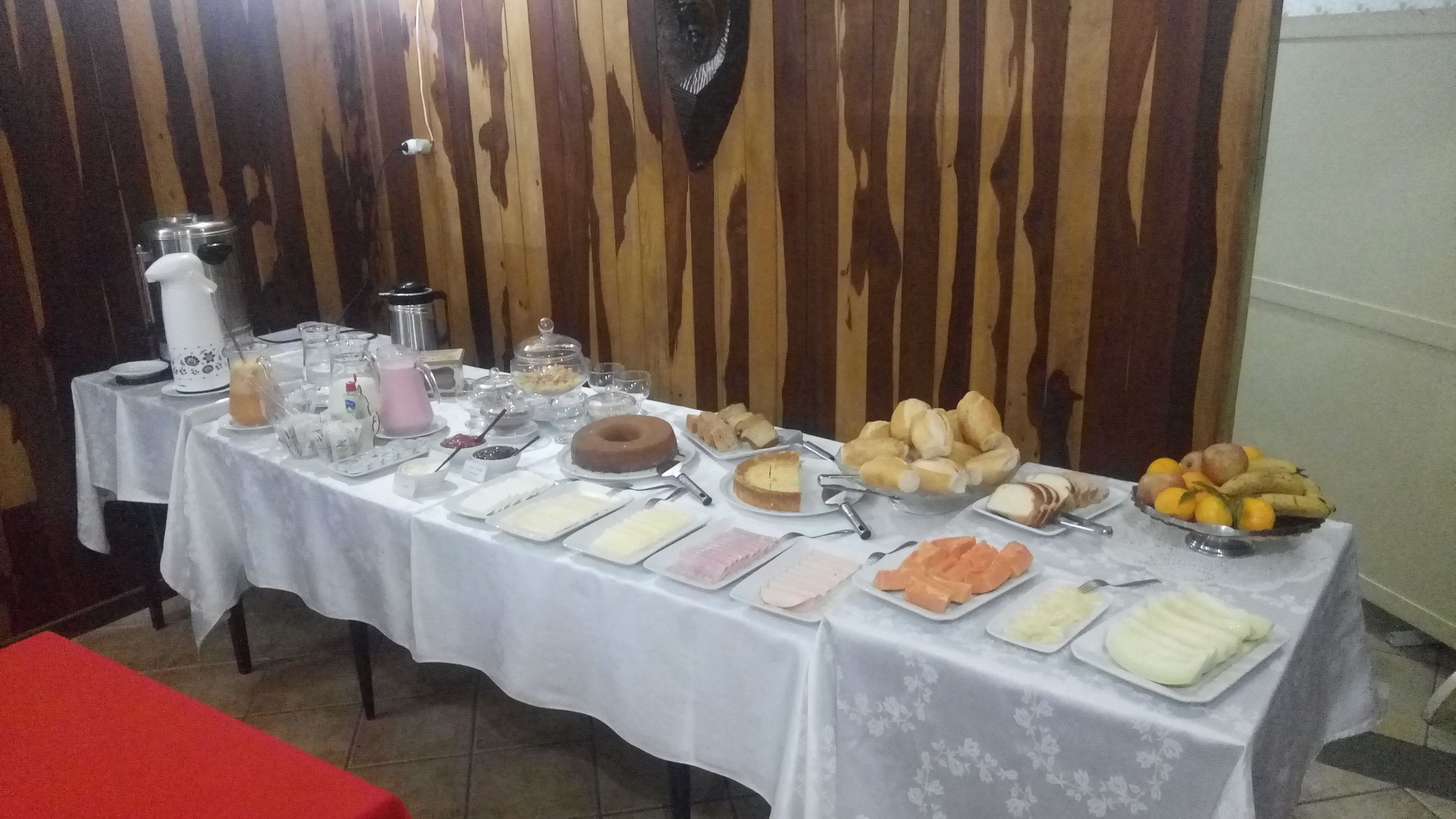 A buffet table with various food items and beverages, set against a wooden wall.