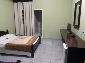 A bedroom with a bed, a desk, a computer, and a mirror. - Kontiki Hotel (São Francisco do Sul)
