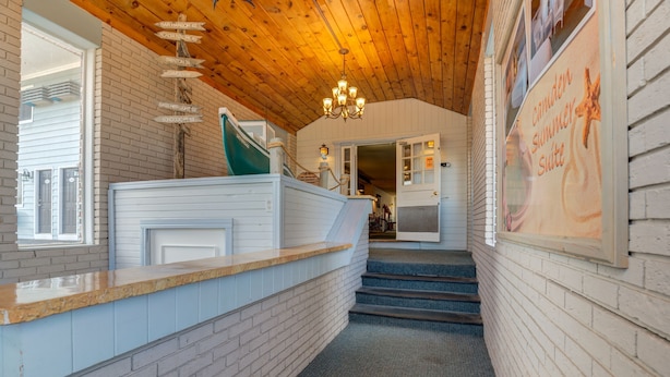 Un escalier menant à une pièce dont le plafond est en bois et sur laquelle est apposée une enseigne indiquant qu’il s’agit d’une suite d’été.