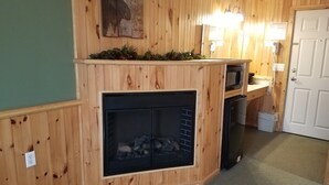 L’intérieur d’une cabane avec un mur en bois, une cheminée, un four à micro-ondes et une porte.