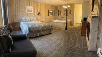 Un dormitorio con una cama grande, una zona de estar, una bañera y paneles de madera en la pared.