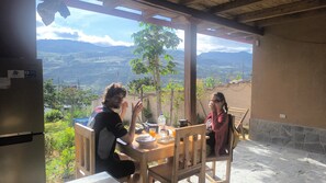 A wooden table with a view of mountains, a bottle of water, and a cup.