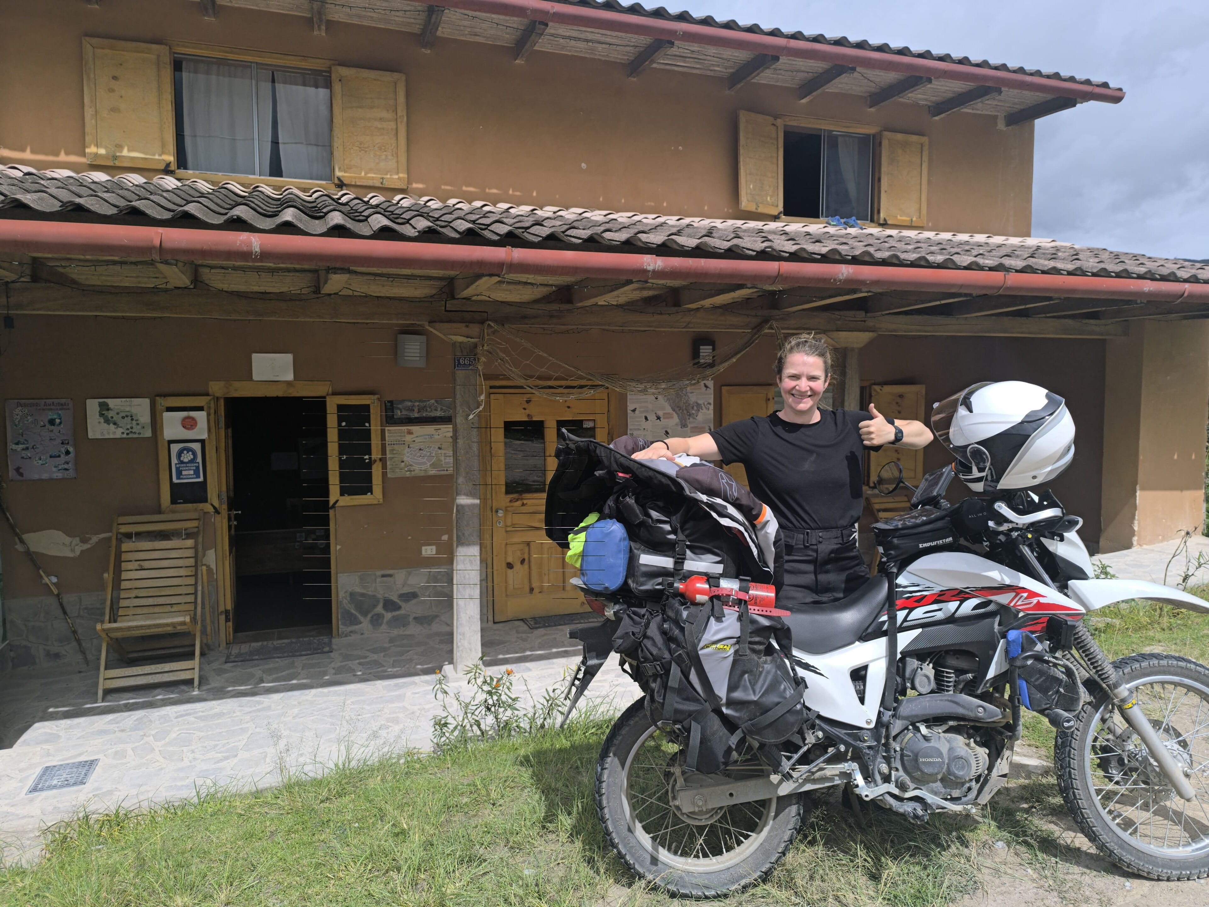 A motorcycle parked in front of a building with a tiled roof and a wooden door.