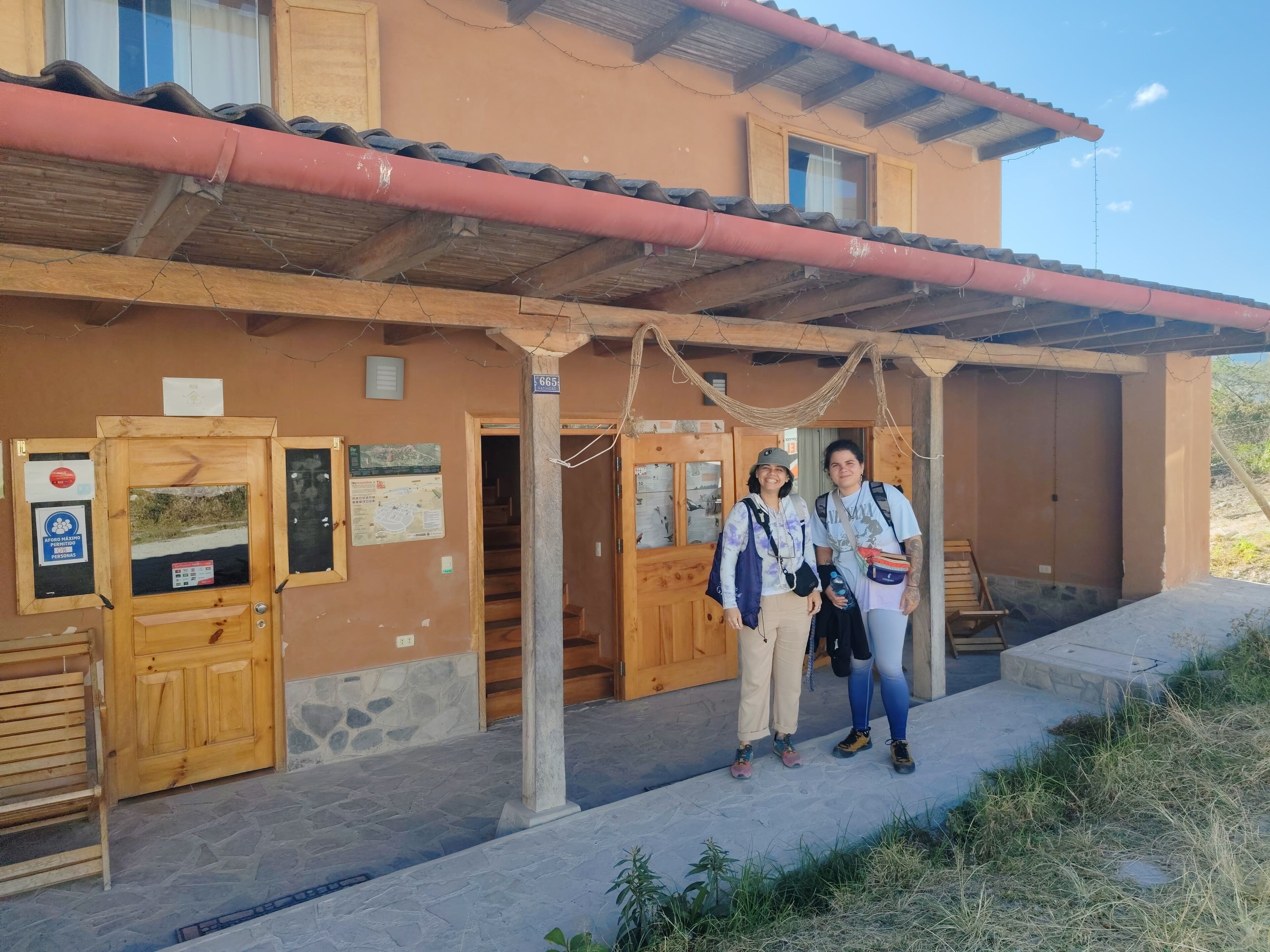 A building with a wooden facade, a tiled roof, and a stone-paved entrance.
