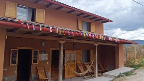 A building with a porch, wooden doors, and a hammock. - Muya (Tingo)