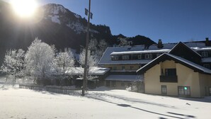 A snow-covered building with a sloped roof, a visible streetlight, and a mountain in the background. - Wiesengrund (Bad Hindelang)