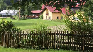 A yellow building with a red roof, surrounded by a well-maintained lawn and a wooden fence. - Wiesengrund (Bad Hindelang)