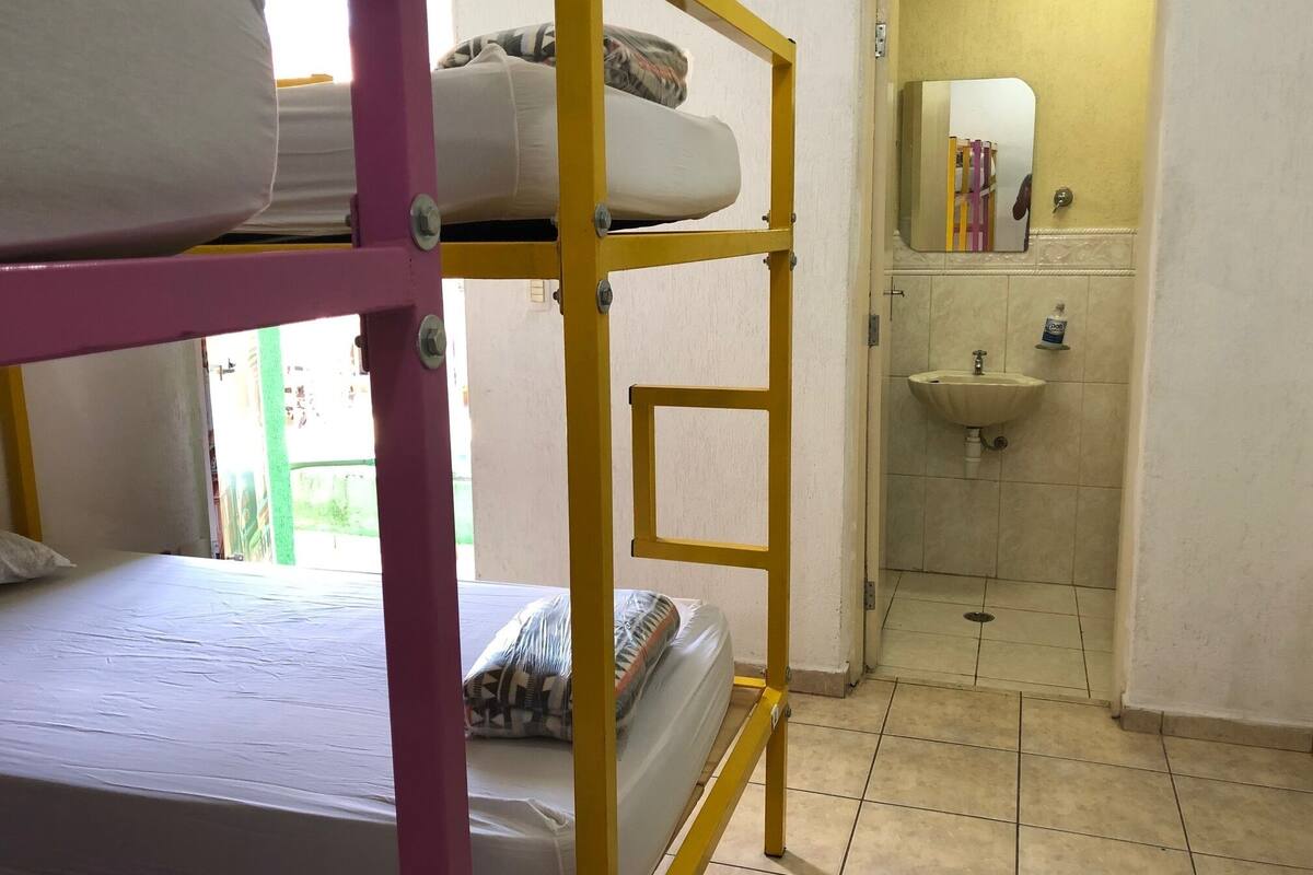 Un dormitorio con literas, un lavamanos y un espejo en el baño.