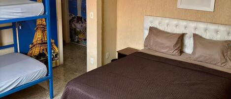 A room with a bed, a bunk bed, and a wall with a picture.