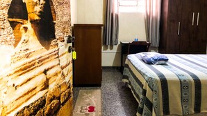 A room with a bed, a wardrobe, a small table, a wall-mounted picture, and a window with curtains. - Zen Garden Hostel (São Paulo)