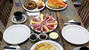 A dining table with various food items, plates, and utensils. - Zen Garden Hostel (São Paulo)