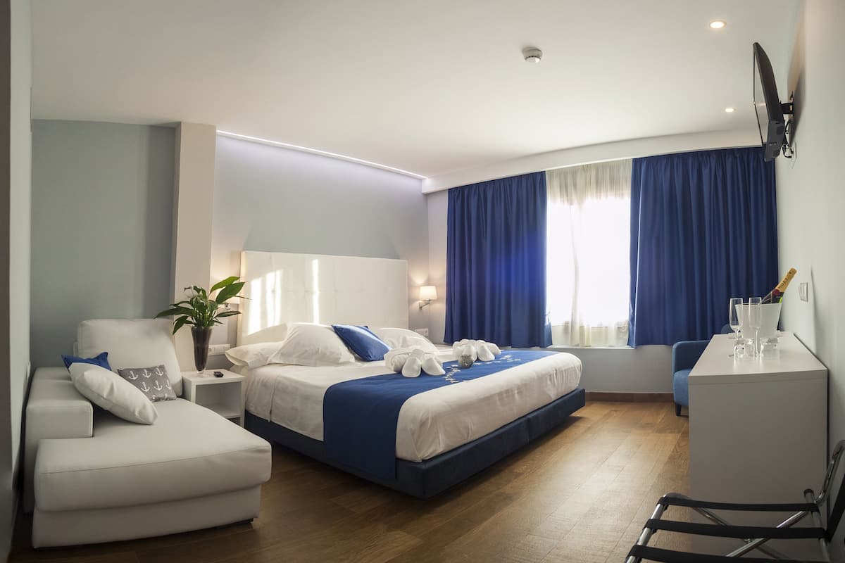 Une chambre d’hôtel avec un lit, un canapé, un bureau et une chaise.
