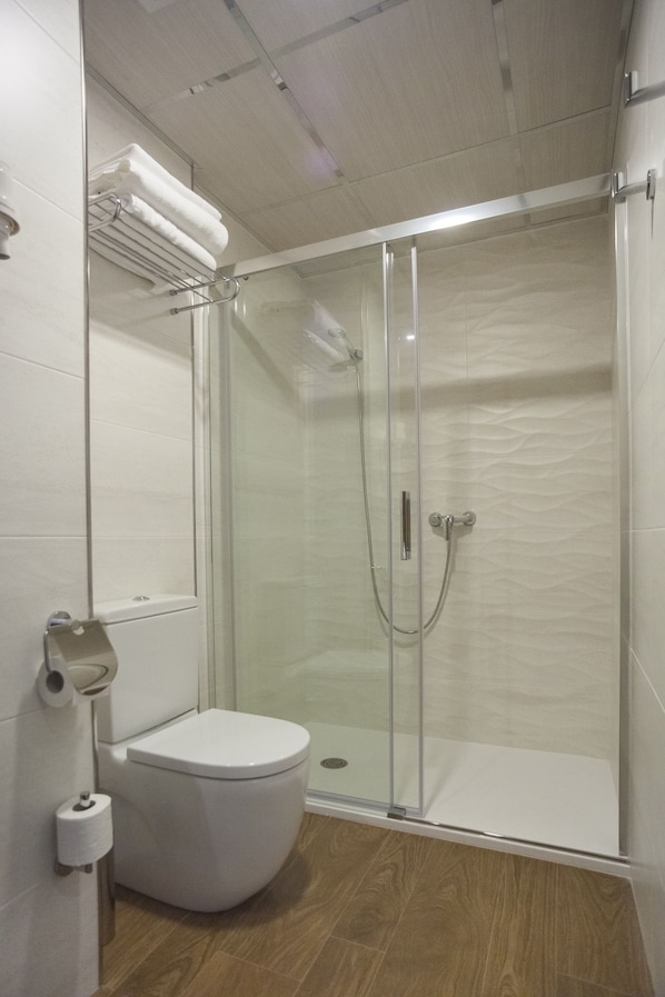 A modern bathroom with a glass-enclosed shower, a toilet, and a towel rack. - Hotel Boutique Barra Alta - Adults Only (Peniscola)