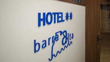 Un letrero de hotel con el nombre "HOTEL" y "barrio alta" escritos en azul.