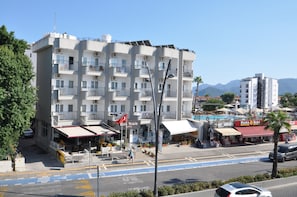 A multi-story hotel with balconies, a visible restaurant, and a street in front.