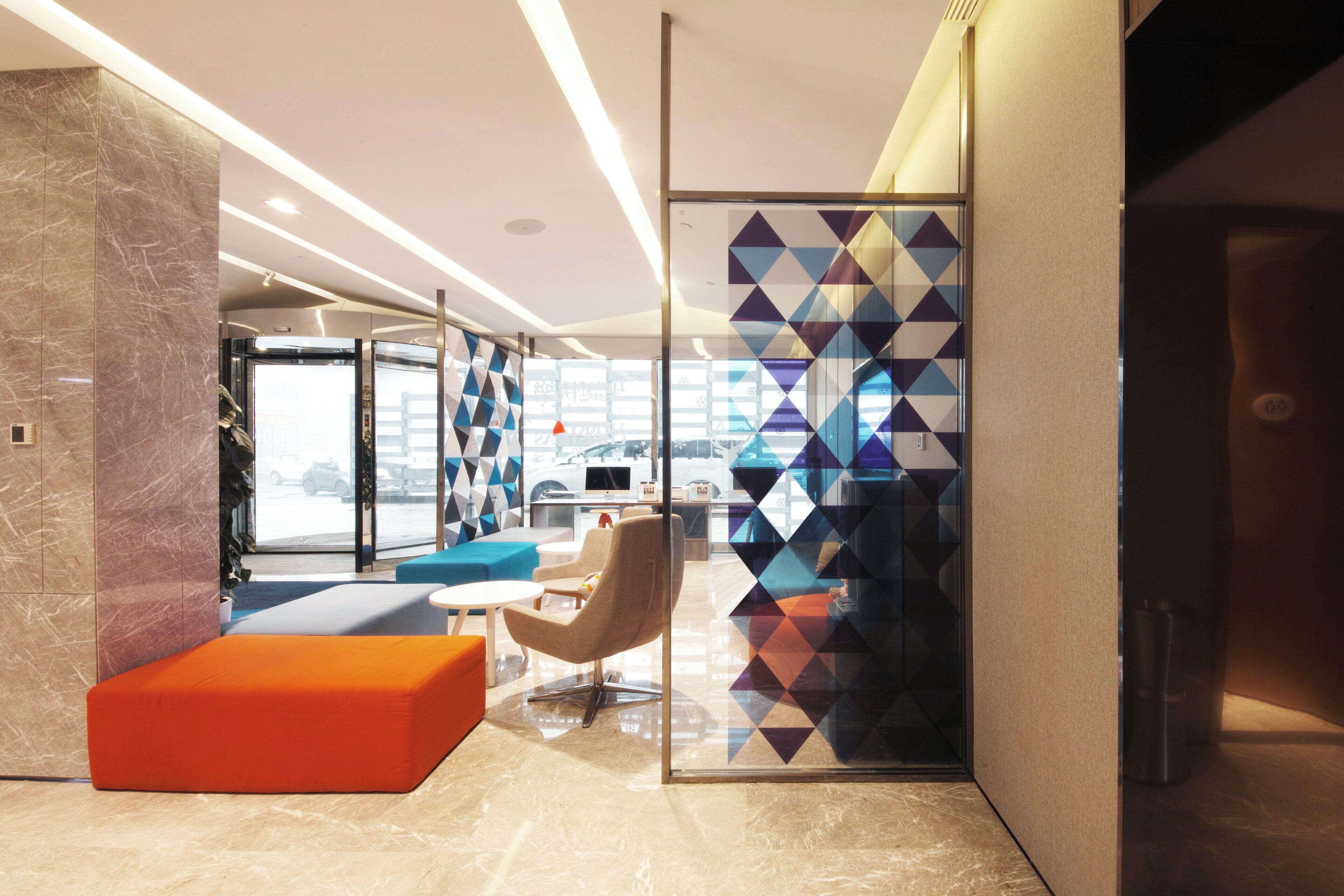 A modern interior with a seating area, a glass partition, and a view of the outside.
