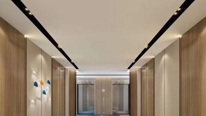 A modern hallway with wooden paneling, a patterned carpet, and recessed lighting. - Holiday Inn Express Hefei Shushan by IHG (Hefei)