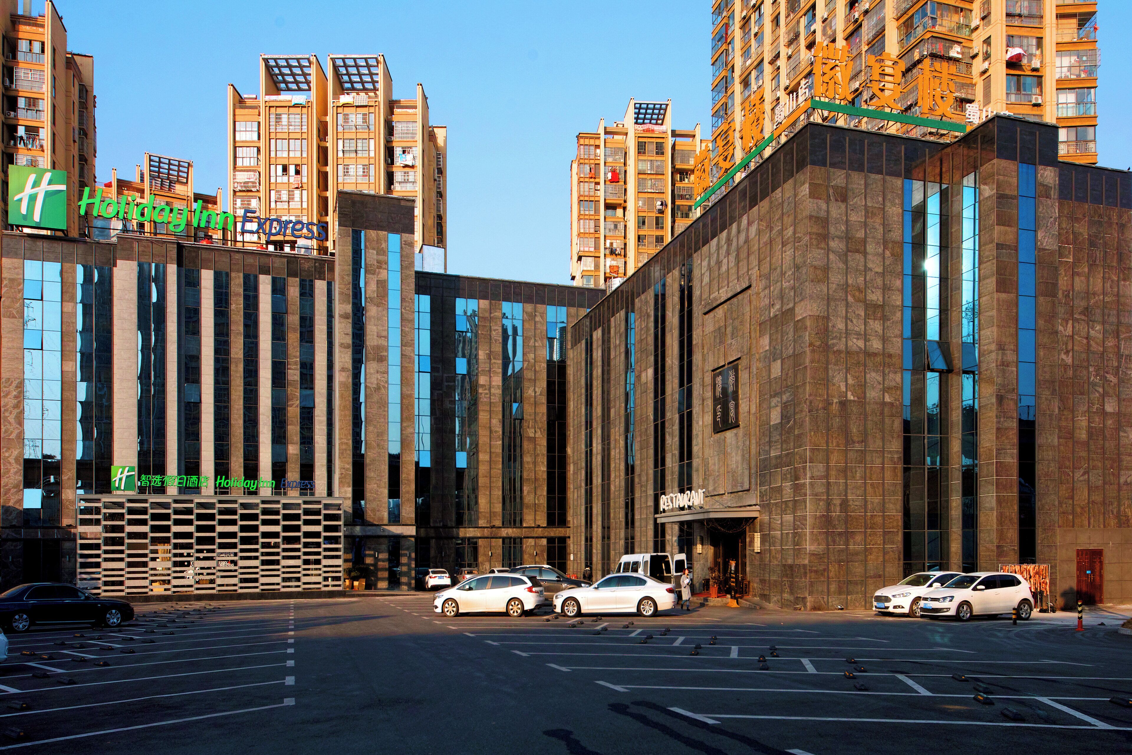 En moderne bygning med et Holiday Inn Express skilt, store vinduer og indgangen til en restaurant.