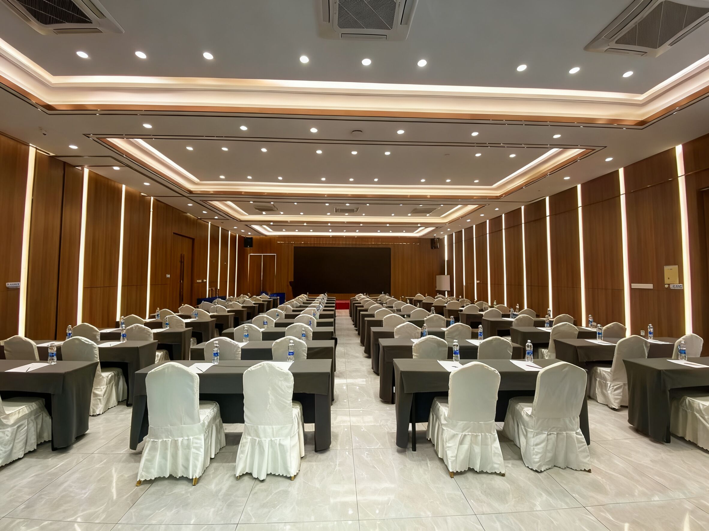 A conference room with rows of tables and chairs, equipped with water bottles and nameplates.