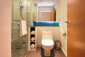 A modern bathroom with a glass shower enclosure, a toilet, and a towel rack.