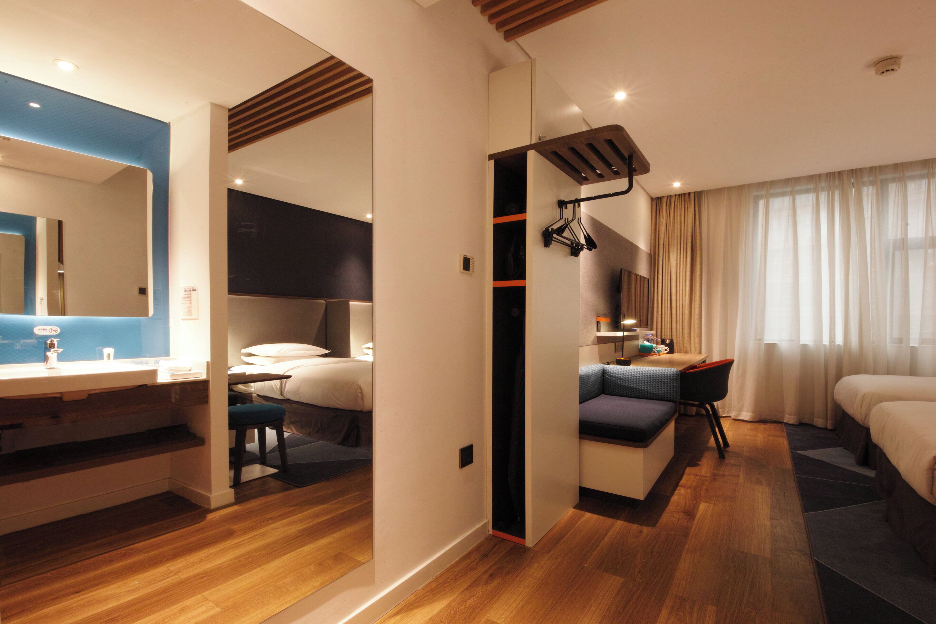 A modern hotel room with a bathroom, a sitting area, and a bed.