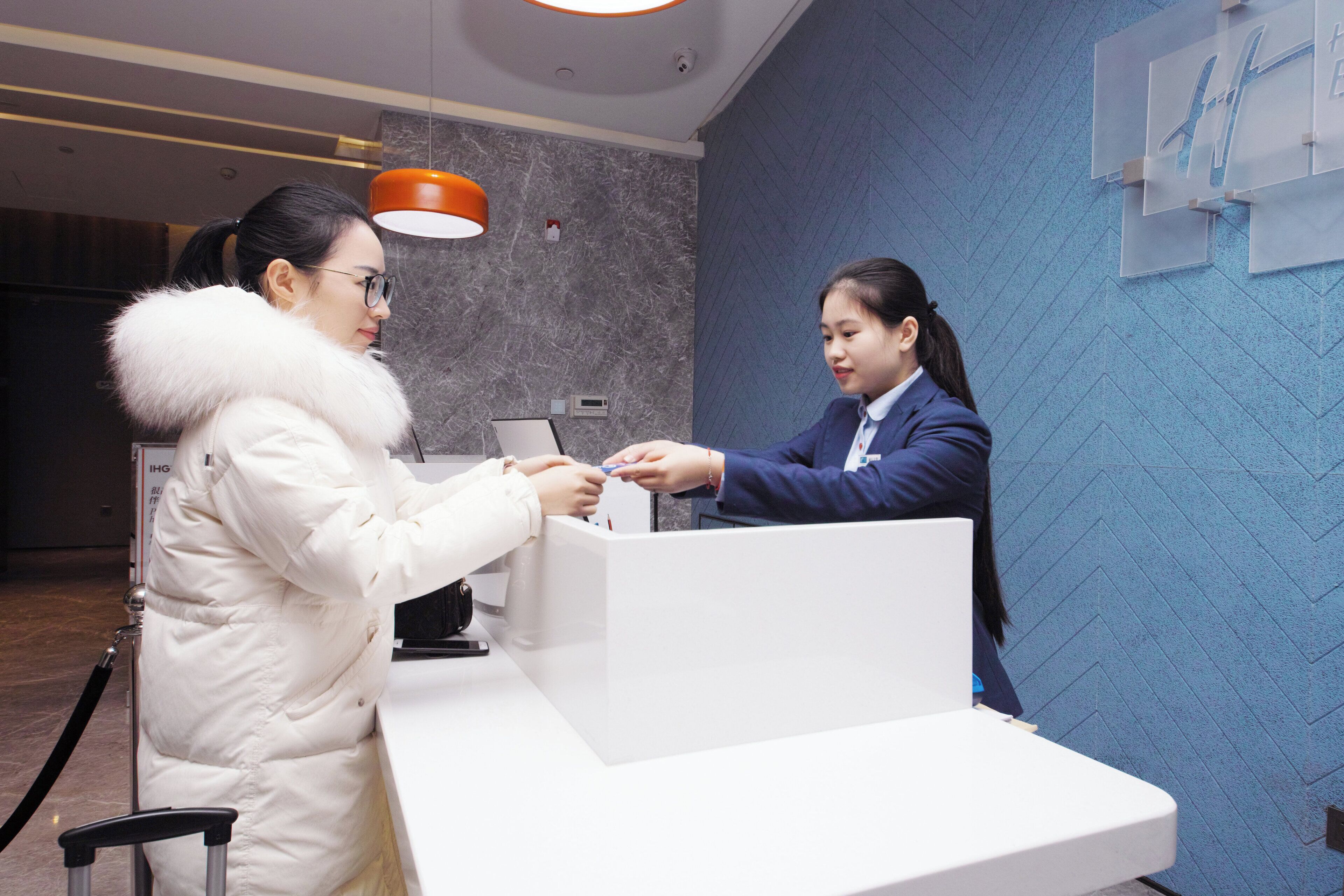 A reception desk with a white counter, a digital scale, and a wall-mounted sign with text.