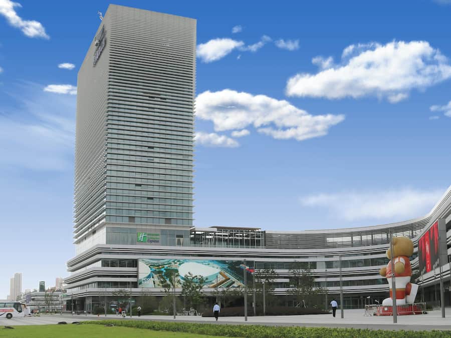 Un edificio moderno con una estructura vertical destacada y un añadido curvo.