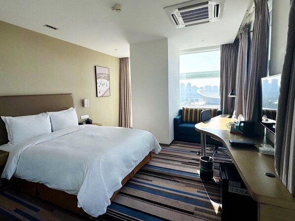 A hotel room with a large bed, a desk with a chair, a view of a cityscape, and a window with curtains. - Holiday Inn Express Suzhou Industrial Park by IHG (Suzhou)