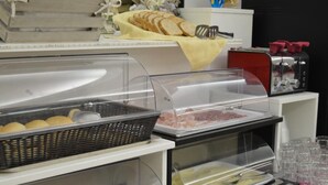 A buffet area with various food items, including bread, meat, and a basket of rolls. - Hotel Dear (Rimini)