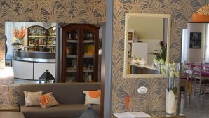 A modern living room with a sofa, a side table with a vase, a mirror, and a decorative cabinet. - Hotel Dear (Rimini)