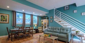 A living room with a dining area, a sofa, a staircase, and a cabinet.