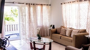 A living room with a glass coffee table, a sofa, and a small side table.