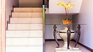 A staircase with a glass table and vase, a wall art piece, and a blue mat at the bottom.
