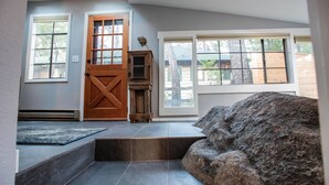 Habitació amb un gran finestral, una porta de fusta i una paret de pedra.