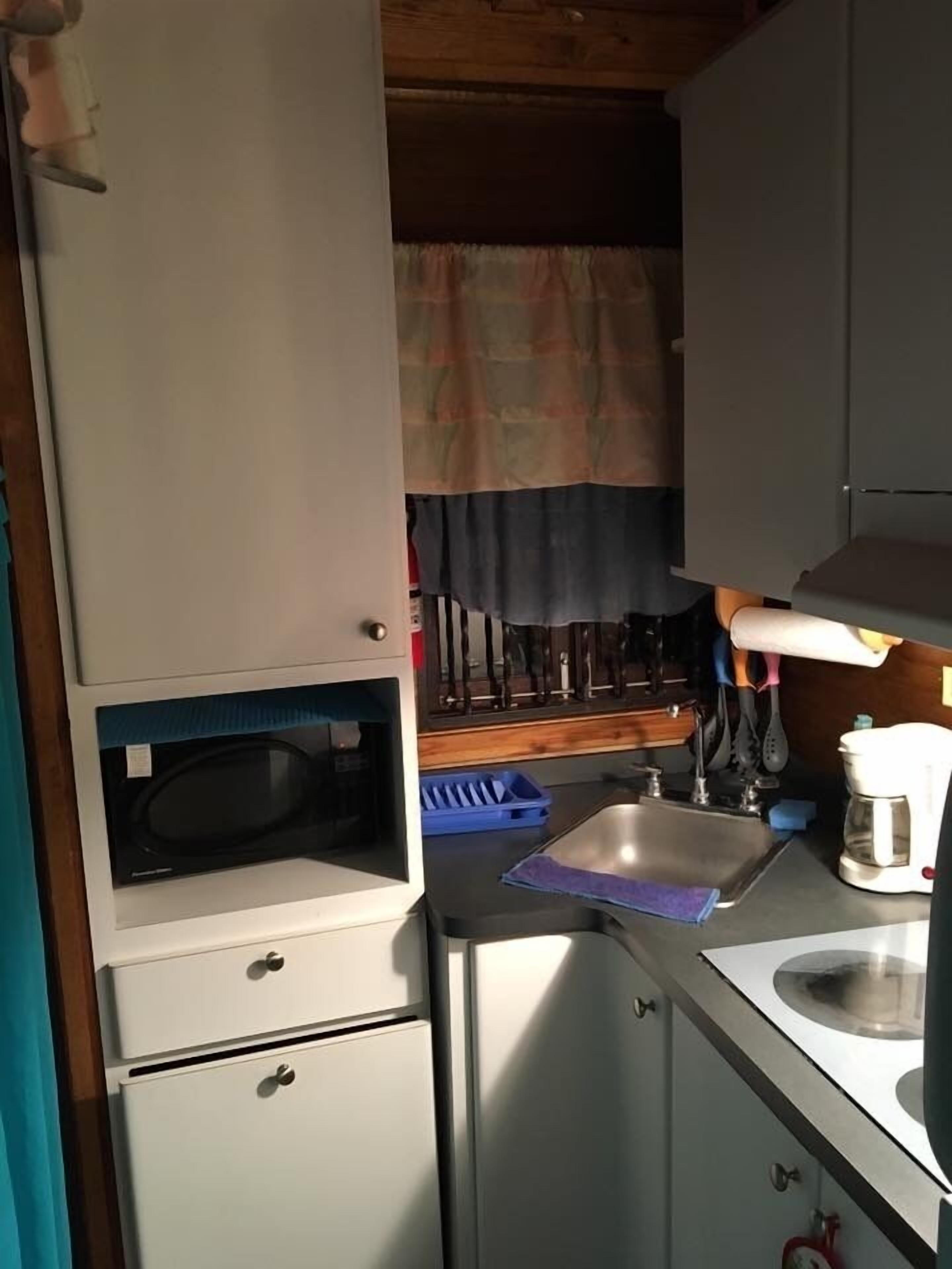 A compact kitchen with a microwave, sink, and coffee maker.