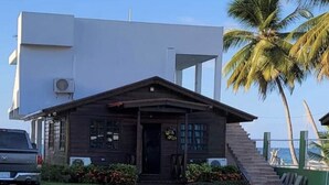 Una casa moderna a due piani con un portico in legno scuro e una parte superiore bianca.