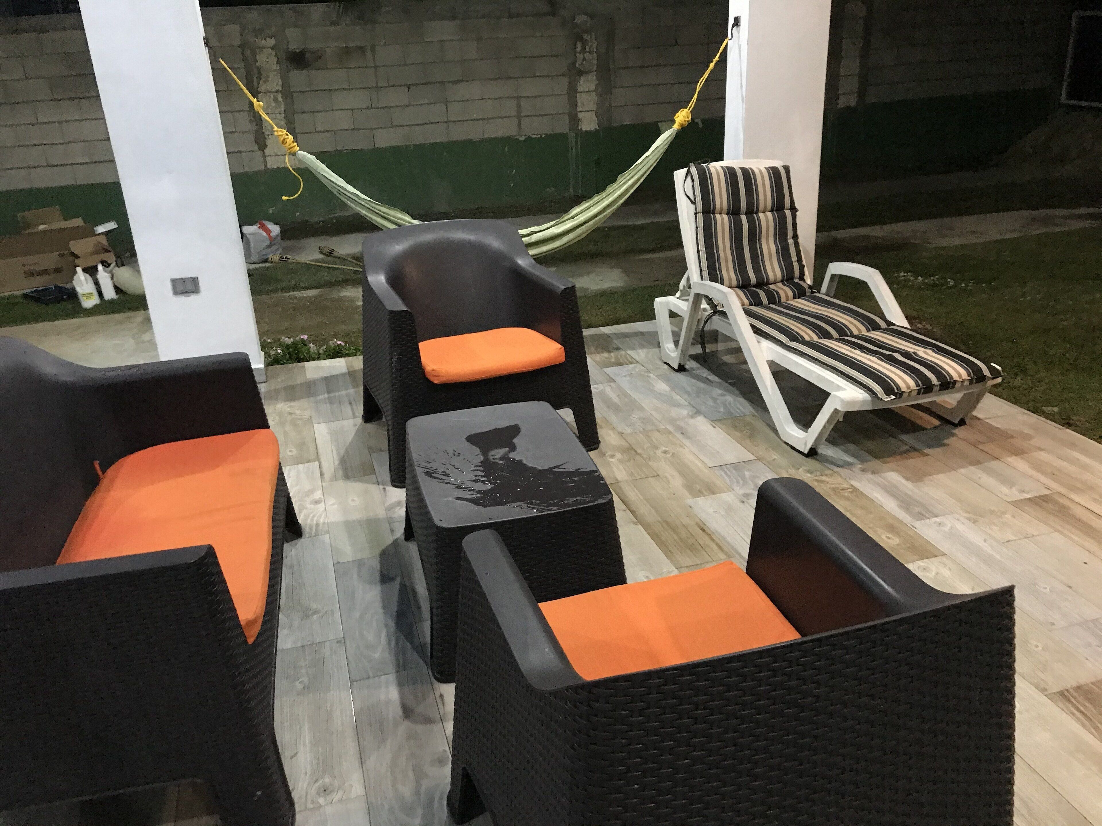 An outdoor patio area with wicker furniture, including chairs and a table, and a hammock.