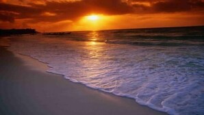 Una spiaggia al tramonto, con il sole che scompare sull'oceano.