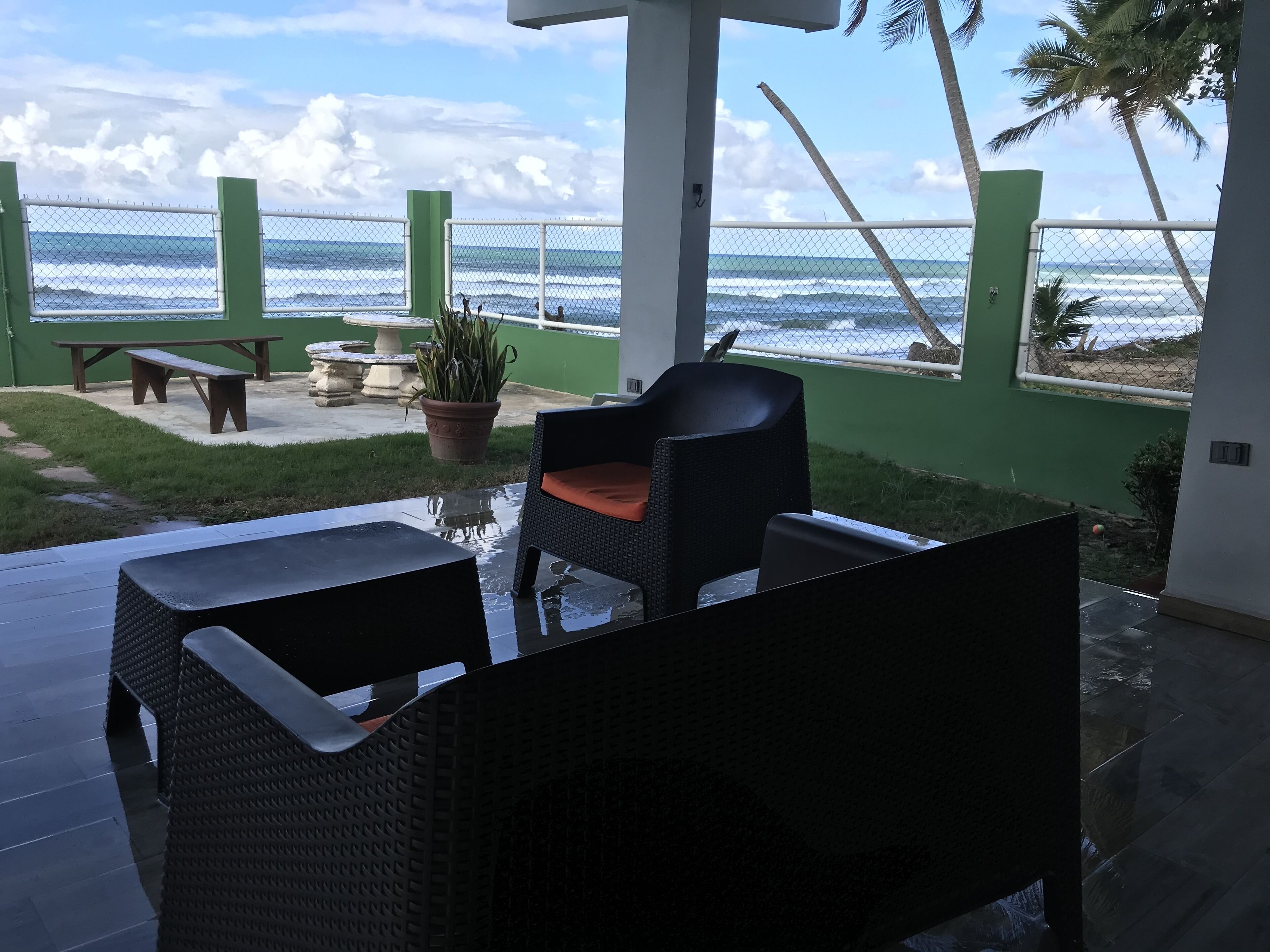 Une terrasse avec vue sur l’océan, une table, des chaises et une plante en pot.