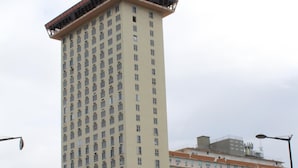 A tall hotel with a flat roof and numerous windows, surrounded by parked cars and palm trees. - Apex living in Puerto Rico's capital  (Santurce)