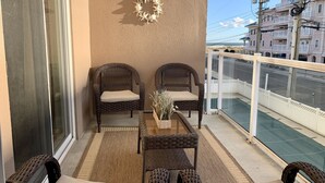 A balcony with wicker furniture, a glass table, and a decorative wreath.