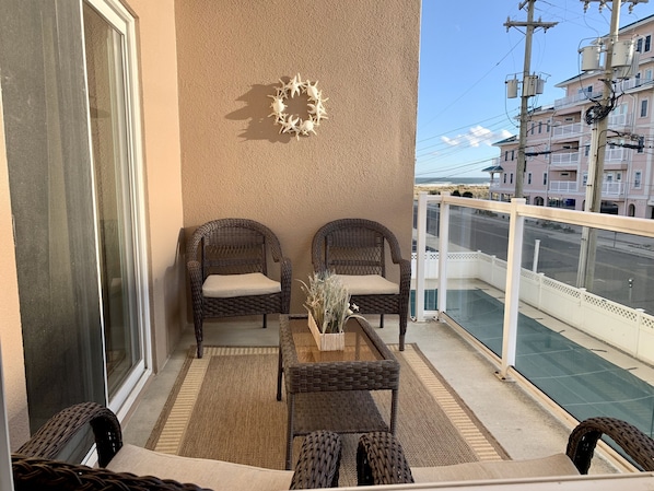 Ein Balkon mit Korbmöbeln, einem Glastisch und einem dekorativen Kranz.