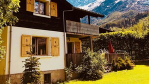 Een chalet met balkon, houten luiken en een berg op de achtergrond.