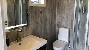 A modern bathroom with a large mirror, a white sink, a toilet, and a glass shower enclosure. - Afternoon cottages near Hella, Hekla & Landmannalaugar (Hella)
