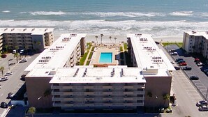Un hotel con piscina centrale, numerosi balconi e vista sull'oceano.