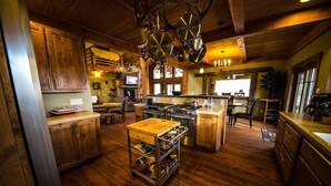 A rustic kitchen with wooden cabinets, a central island, and hanging pots. - Fly Fisherman's Lodge on the Bitterroot River,  Lolo Mt (Lolo)
