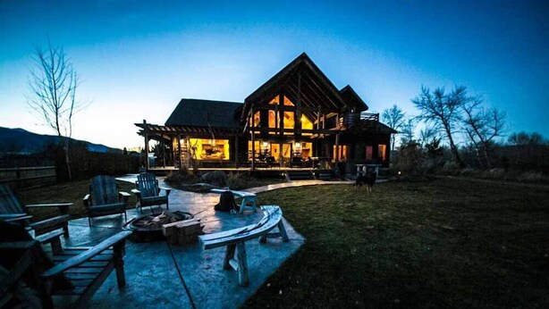A large log cabin with a covered patio area, outdoor seating, and a fire pit. - Fly Fisherman's Lodge on the Bitterroot River,  Lolo Mt (Lolo)